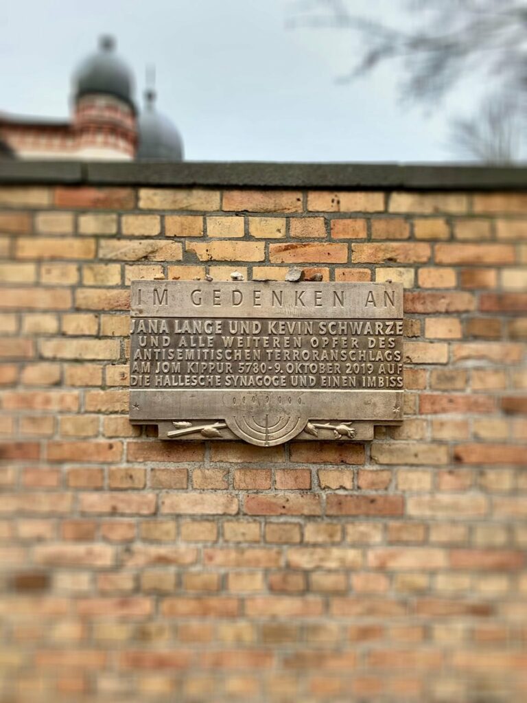 Eine Tafel an der Mauer der Synagoge erinnert an den Anschlag eines Rechtsradikalen in Halle. Der Mann versuchte, mit selbst gefer- tigten Waffen die Synagoge zu stürmen und ein Blutbad anzurichten. Als ihm das misslang, erschoss er in der nahegelegenen Innenstadt zwei Menschen und verletzte weitere. Foto: Tobias Großekemper